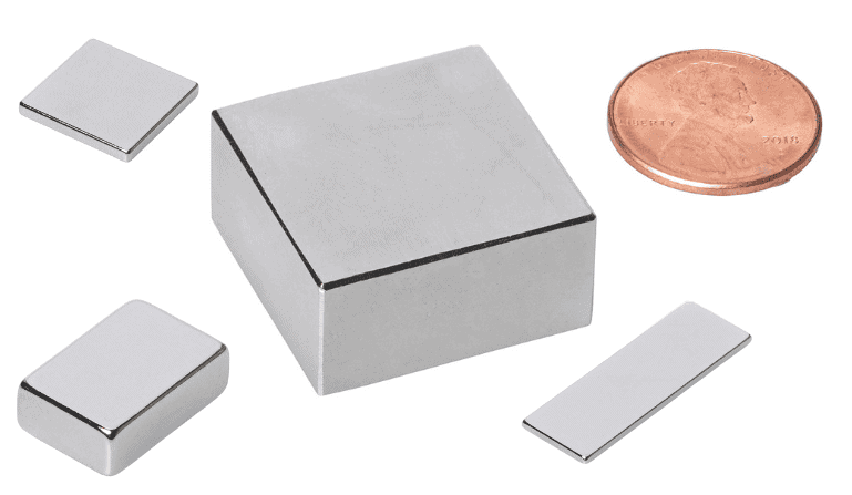 Four neodymium block magnets of varying sizes next to a penny for scale.