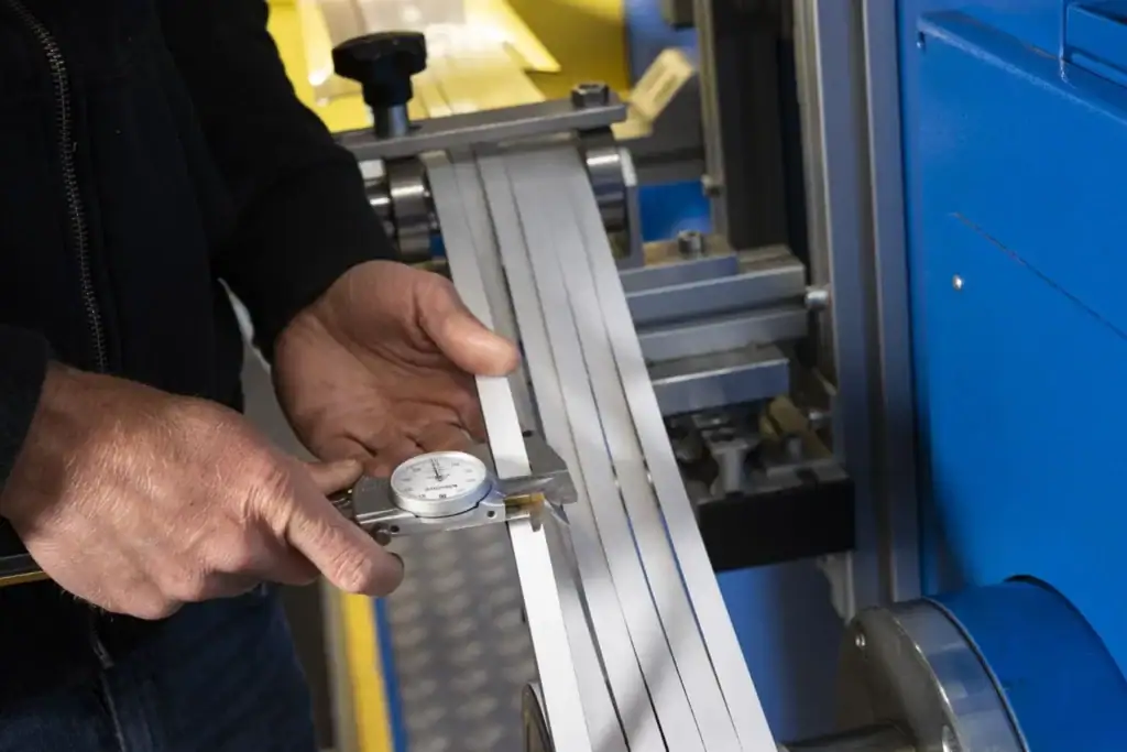 Factory worker operating a slitting machine, cutting wide rolls into narrow strips.