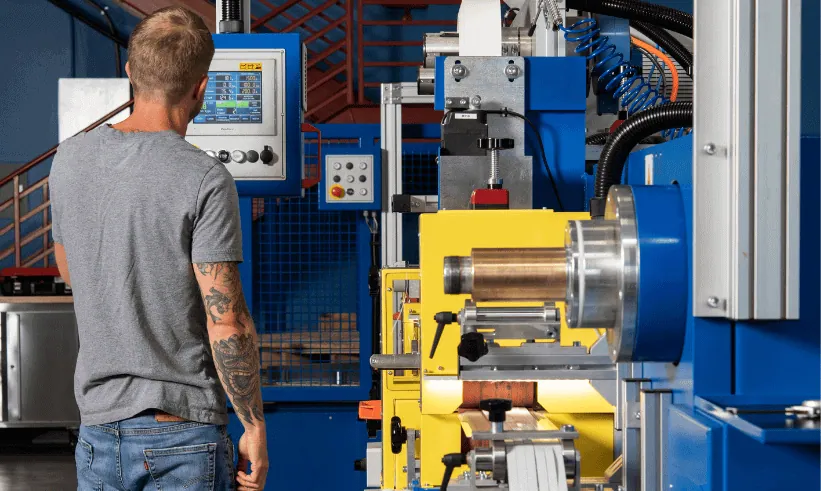 Man operating blue and yellow industrial machinery.